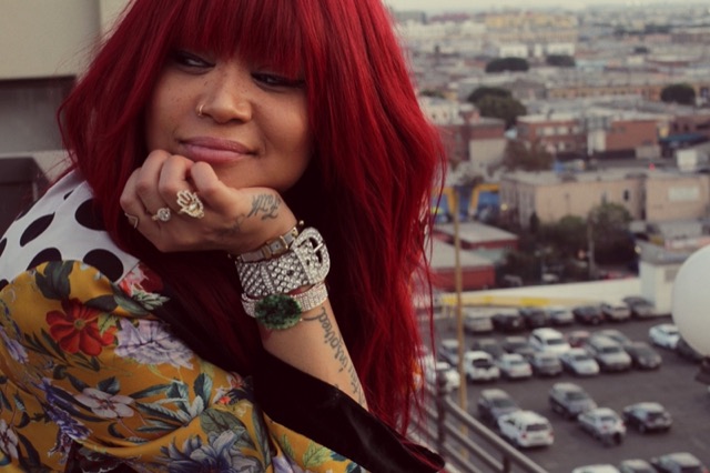 Tiffany Red smiling on a rooftop above the city